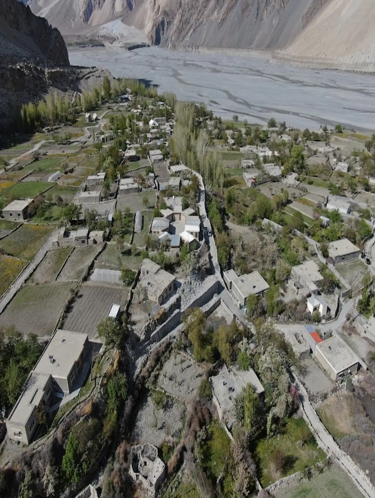 Aerial view of a terraced mountain village along a river in Gilgit-Baltistan