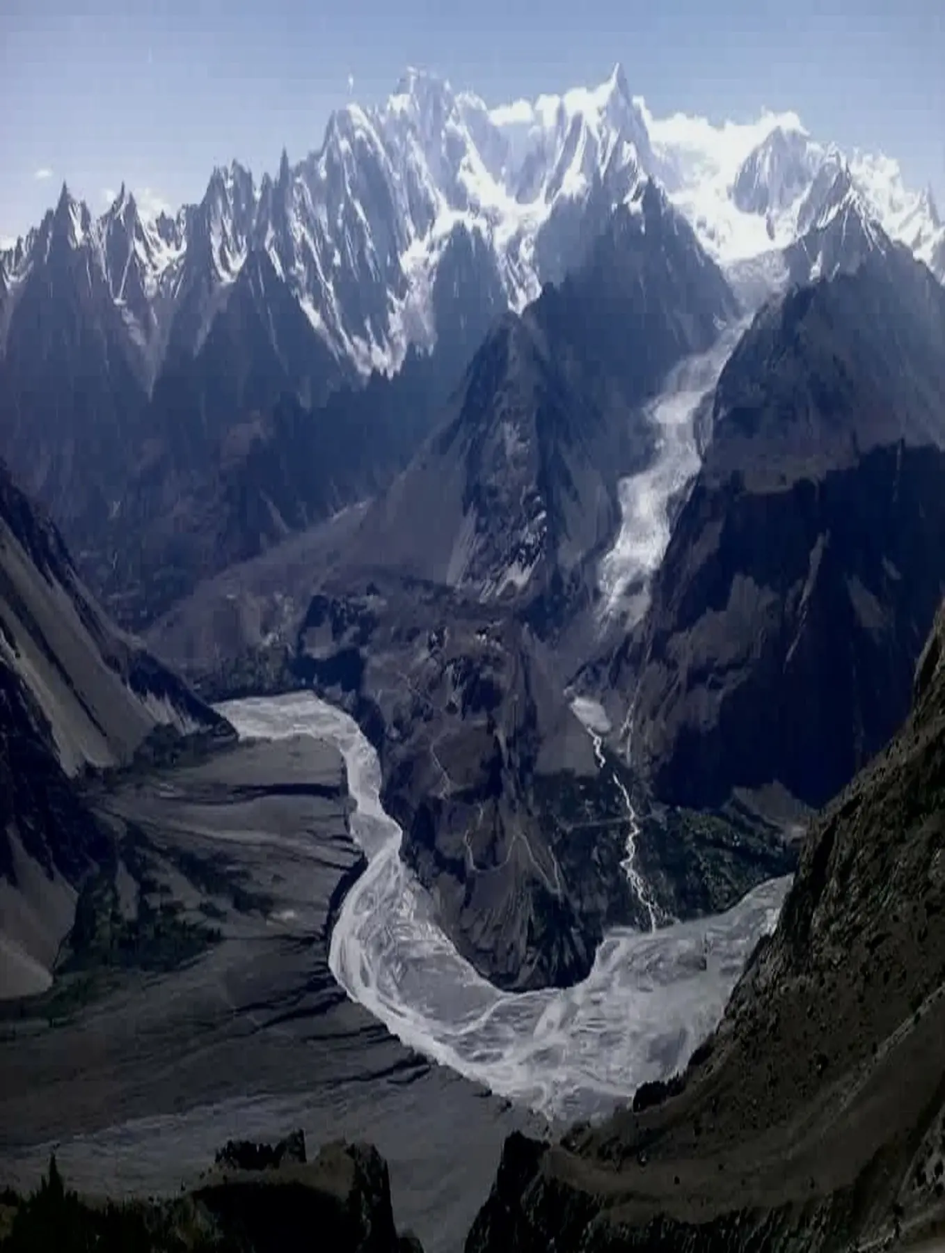 Wide aerial view of a curving glacial river cutting through the Karakoram mountains